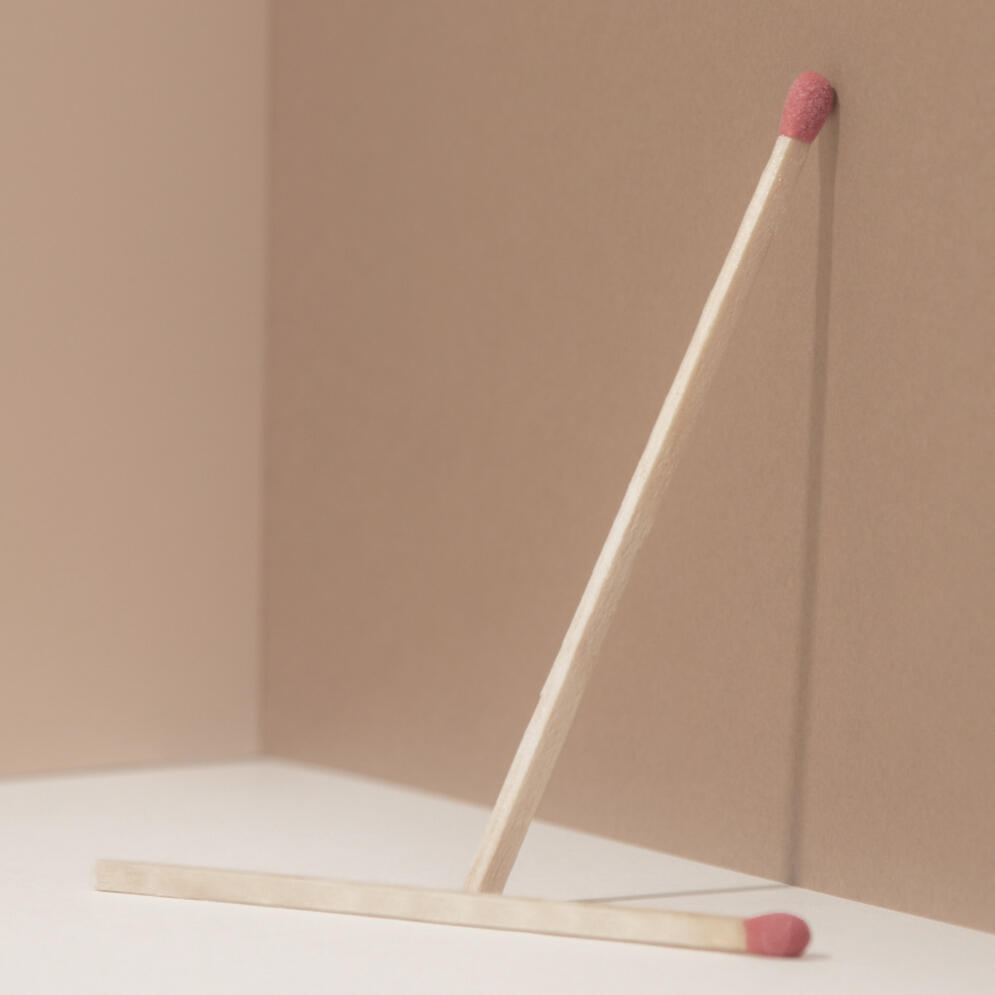 Foto von einem stehenden und einem liegenden Streichholz, inspiriert vom Satz „Pause ist ein Zustand, kein Ort“.