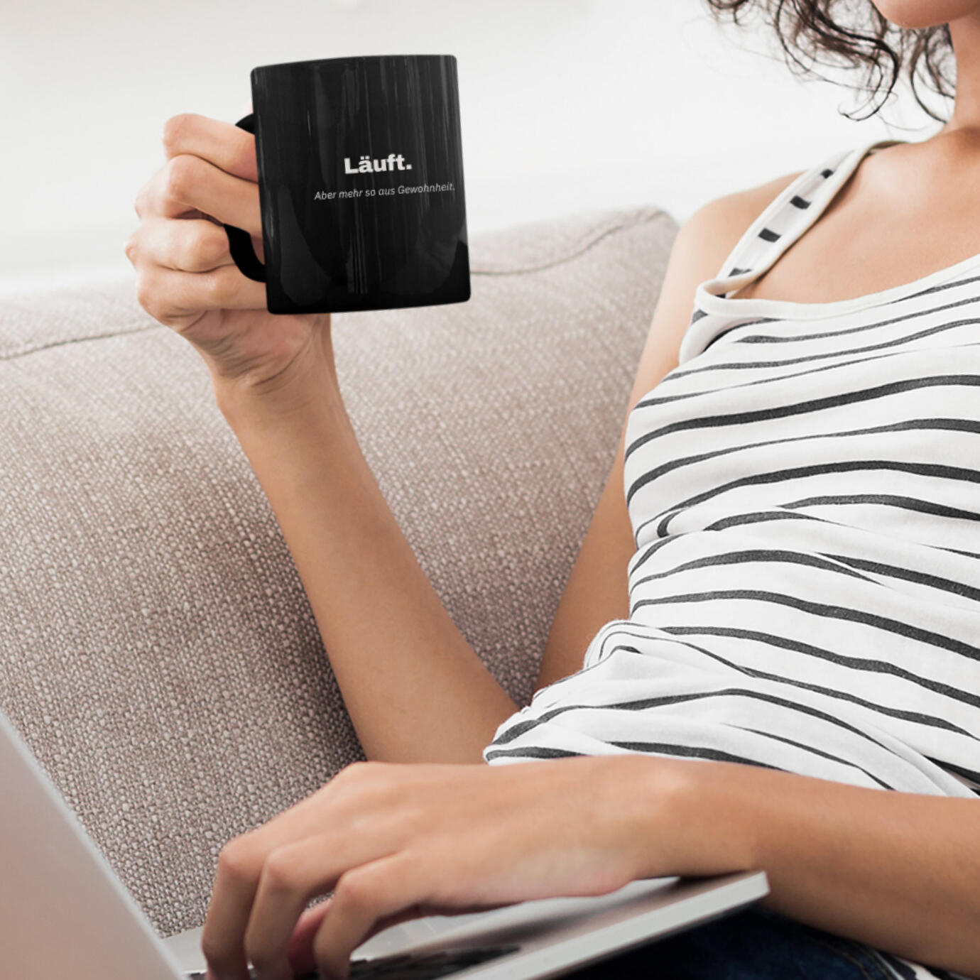 Frau hält schwarze Tasse mit dem Satz "Läuft. Aber nur so aus Gewohnheit.".